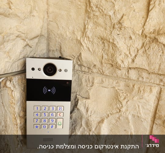 אינטרקום עם מצלמה ומקשים מוארים על קיר אבן